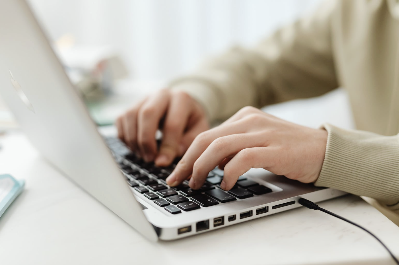 Person tippt konzentriert an einem Laptop in hellem Büro
