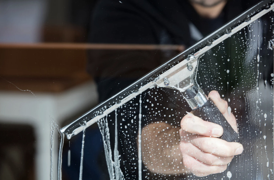 Nahaufnahme professioneller Glasreinigung mit Abzieher